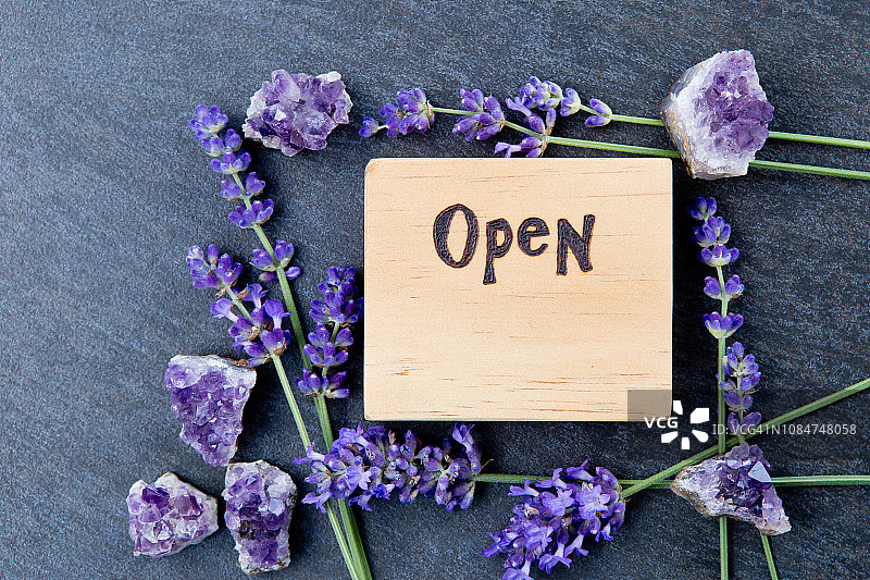 开放标志替代疗法业务-字燃烧木材与紫色薰衣草花和紫水晶簇图片素材