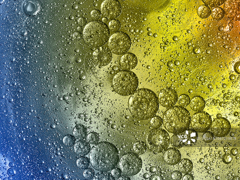 全框架的抽象形状和纹理，形成的气泡和水滴在浅蓝色和黄色液体背景。图片素材