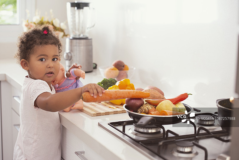 小女孩在厨房里玩蔬菜。图片素材