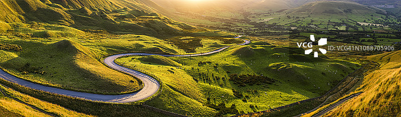 山谷弯弯曲曲的道路在夕阳下大尽收眼底。英语峰区。英国图片素材