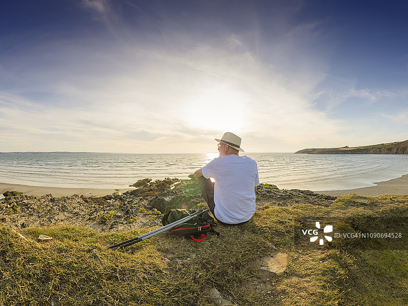 法国，布列塔尼，老男人在海滩上休息，坐在沙丘上图片素材