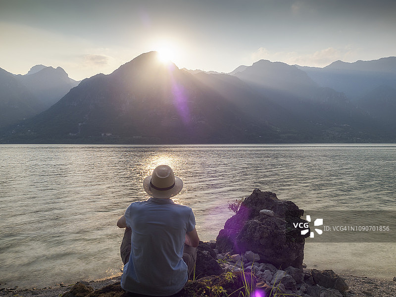 意大利，伦巴第，日落时分坐在伊德罗湖边的男人的背影图片素材