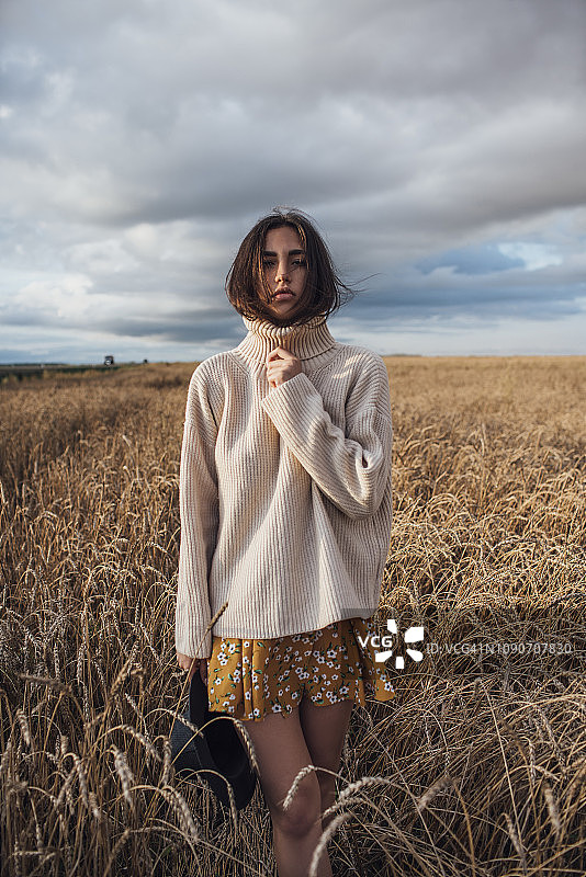 年轻女子的肖像穿着超大的高领套衫站在玉米田图片素材