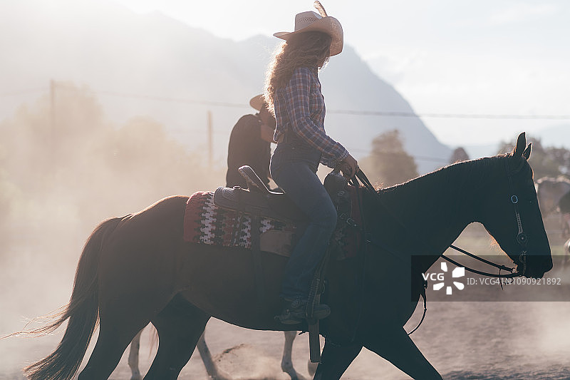 女牛仔骑马在尘土飞扬的马术竞技场，侧面Primaluna，特伦蒂诺-上阿迪杰，意大利图片素材