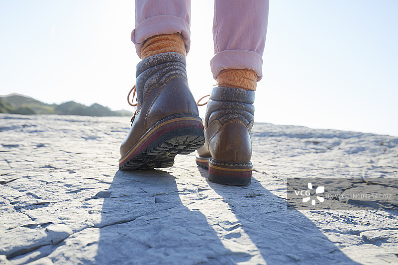 穿着登山靴的女人在海边的岩石上行走图片素材