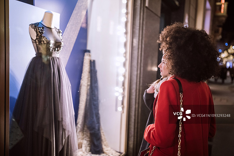 一个女人在商店橱窗里看一件漂亮的新年礼服图片素材