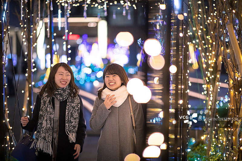 年轻的女性朋友们走在圣诞彩灯下图片素材