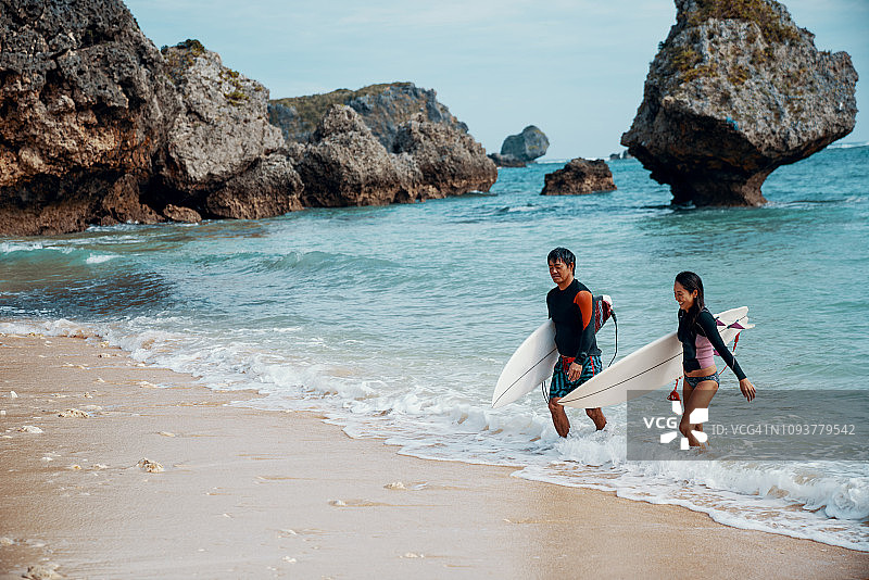 一对成熟的夫妇刚冲浪完就带着冲浪板在海滩上散步图片素材
