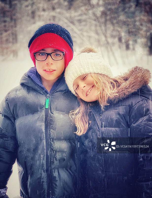 一对在雪中面对相机的兄妹的肖像图片素材