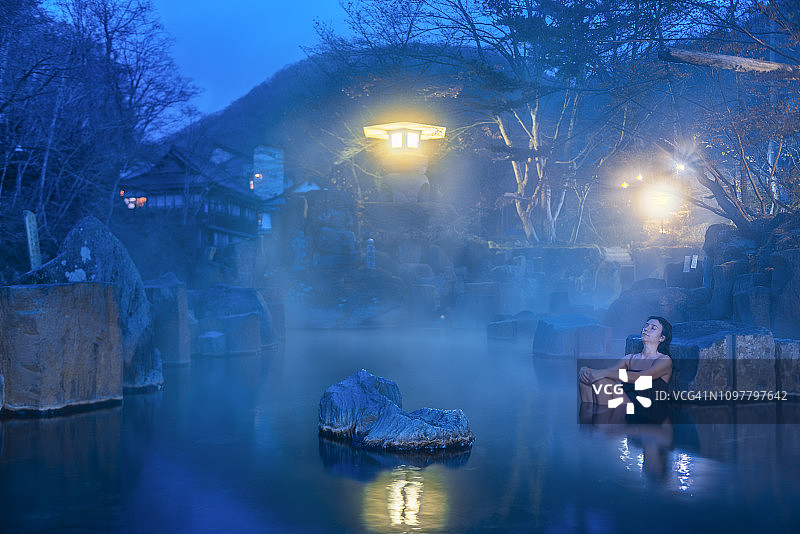 黎明时分，一名女子在日本温泉中放松。图片素材