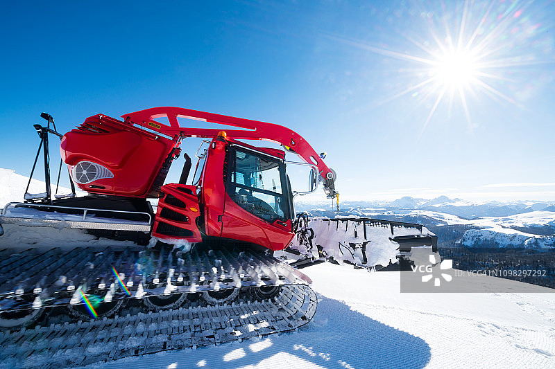 现代红色雪车清除多余的雪和整理滑雪道在一个阳光明媚的日子图片素材