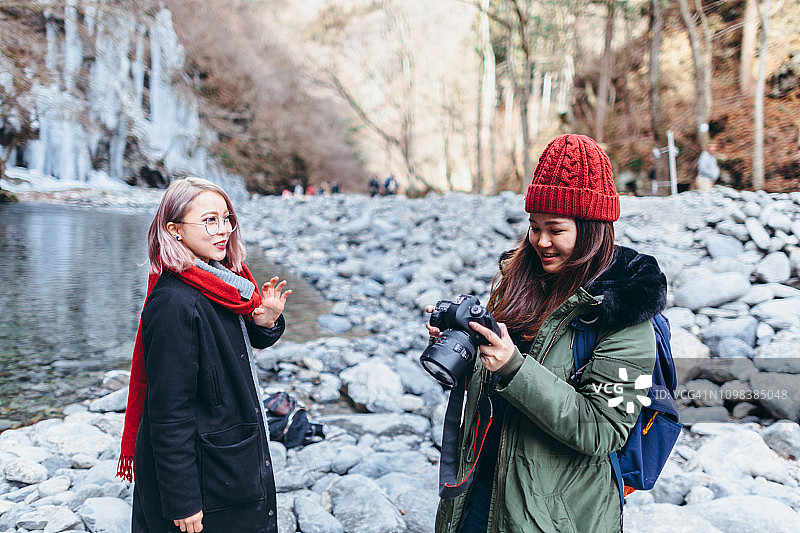 年轻的女游客在山里用单反相机查看照片图片素材