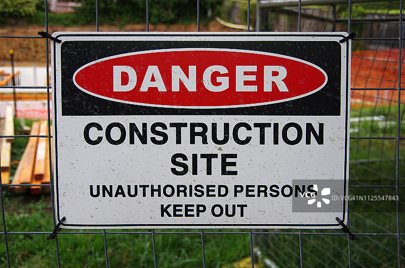 的危险:施工现场。建筑地盘铁丝围栏上的“违例人士请勿入内”标志图片素材