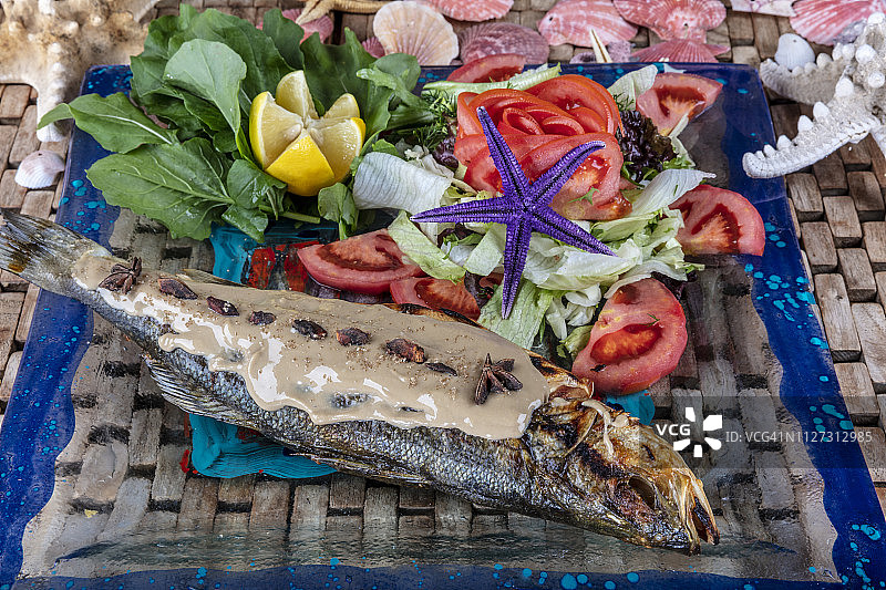 新鲜的鲈鱼。地中海风味的鱼，在煤炉中完全烤制，配以香草和柠檬。图片素材