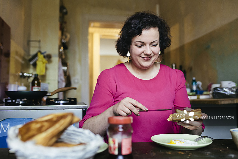 在厨房里吃早餐的女人图片素材