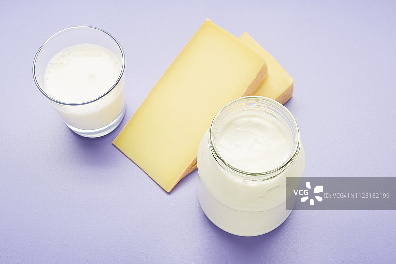 乳制品的静止生命，包括一杯牛奶，奶酪和酸奶在紫色的背景图片素材