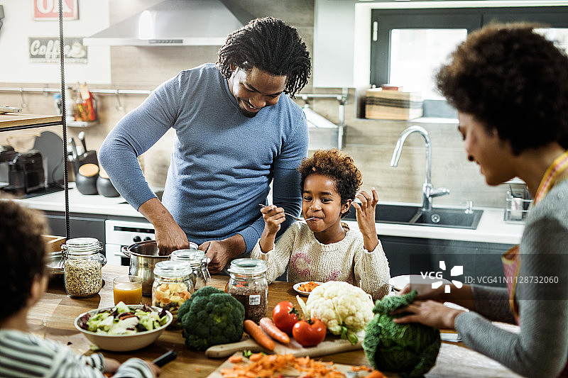 快乐的黑人家庭在厨房准备健康的饭菜。图片素材