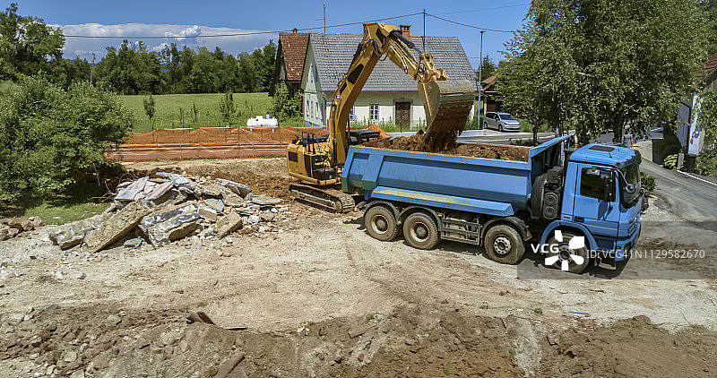 在建筑工地，挖掘机正在把挖出来的土装上卡车图片素材