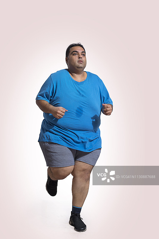 胖子穿着t恤和短裤跑步，穿着运动鞋图片素材