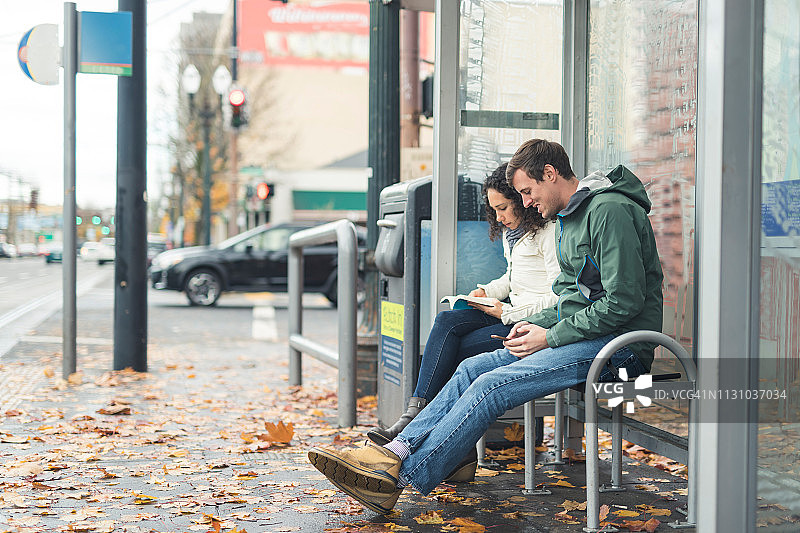 两个朋友在一个城市车站等公共汽车图片素材