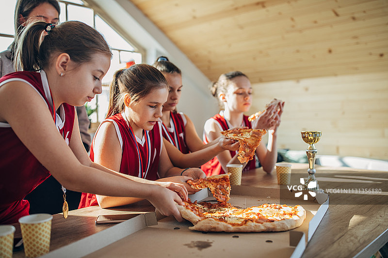 女子篮球运动员在家和教练一起吃披萨图片素材