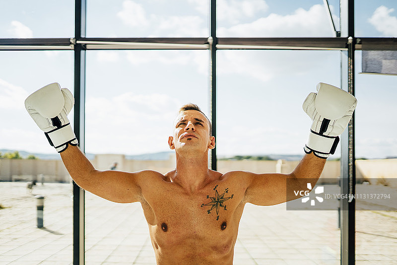 一个拳击手在窗口举起手臂的肖像图片素材