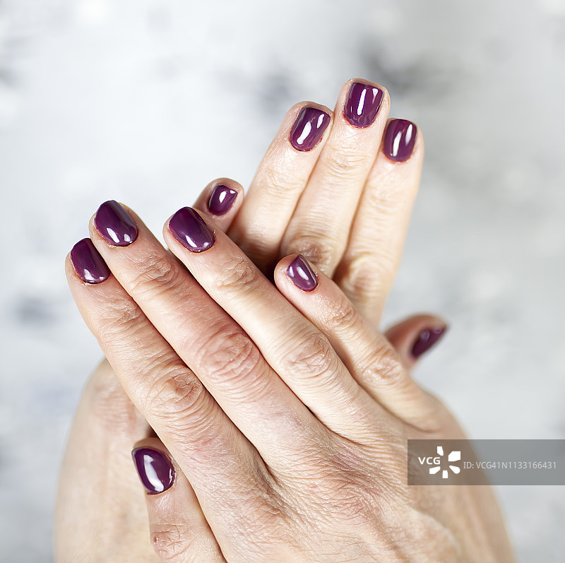 特写的女人手指与指甲艺术。栗色的指甲油图片素材