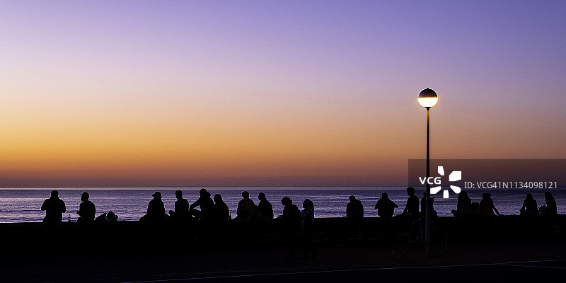 日落时分，人们在海边背光下图片素材