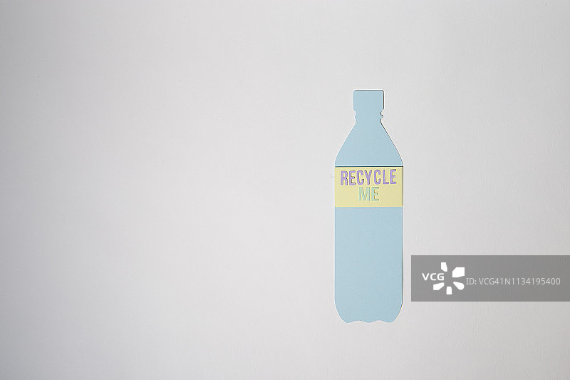 纸上有一个塑料瓶，上面写着“回收我”。图片素材