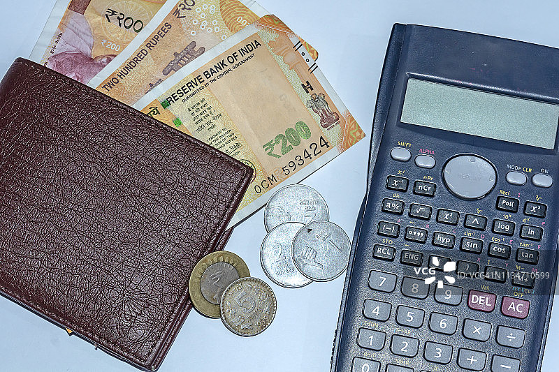 近距离观看计算器，钱包与全新的印度200卢比纸币和1,2,10卢比硬币在白色孤立的背景。图片素材