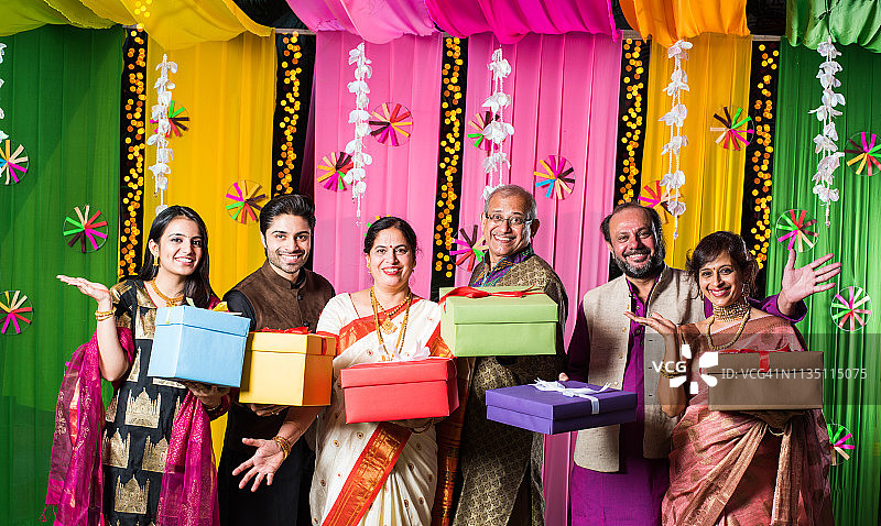 印度家庭在排灯节/婚礼或任何其他仪式上交换/持有礼品盒。站在装饰好的背景上图片素材