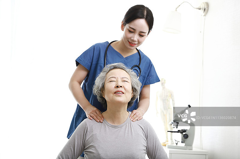 理疗师给老年妇女做肩部按摩图片素材
