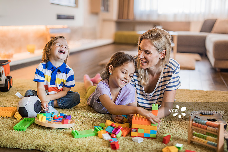 快乐的单身母亲和她的孩子在客厅玩。图片素材