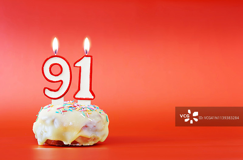 91岁生日。91号白色蜡烛纸杯蛋糕。鲜艳的红色背景与复制空间图片素材