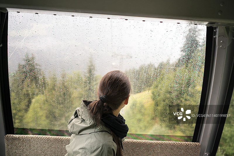 瑞士，瓦莱州，一名女子坐在缆车上望着窗外的雨图片素材