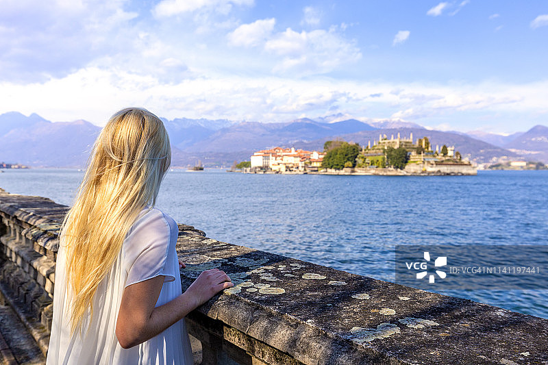 意大利皮埃蒙特马焦雷湖斯特雷萨湖畔，年轻女孩看着伊索拉·贝拉。欧洲。图片素材