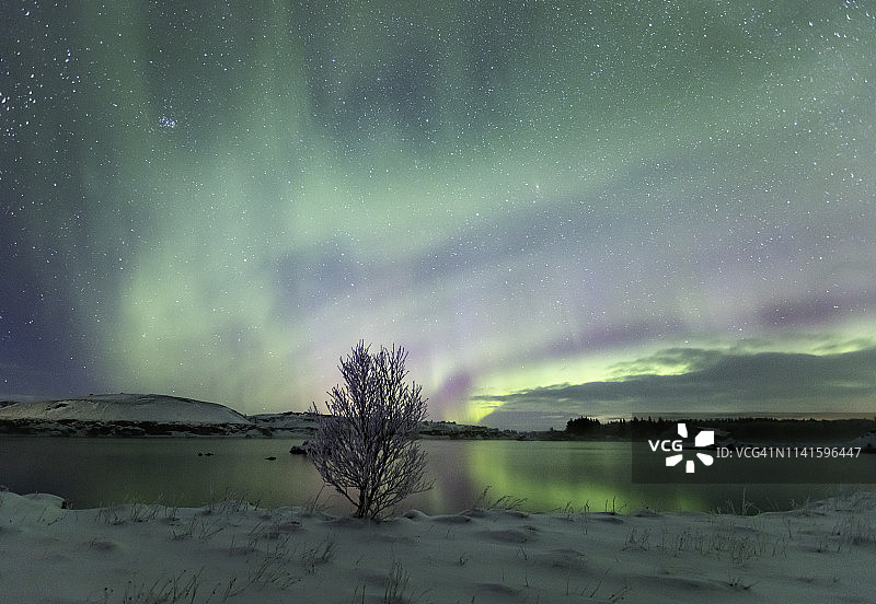 北极光照亮天空，在冰岛的米凡特湖反射图片素材