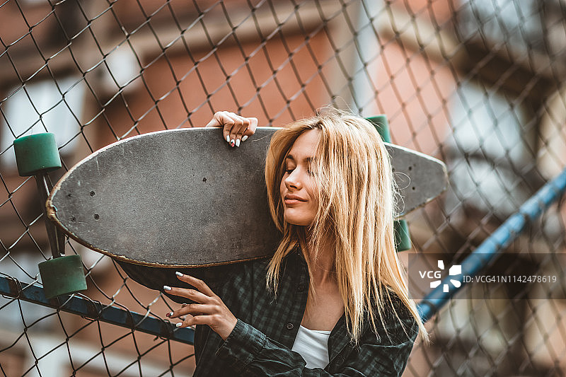 街道肖像积极的年轻女性与滑板在城市图片素材