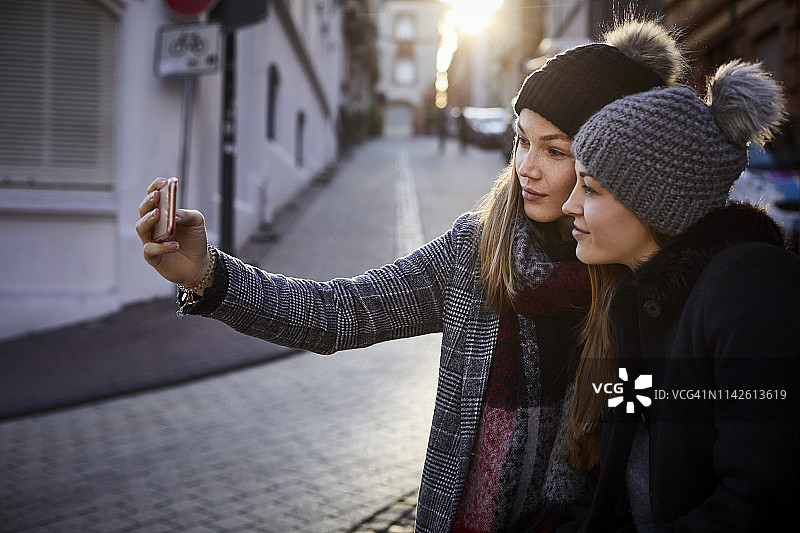 两个年轻女人穿着暖和的衣服在城市里自拍图片素材