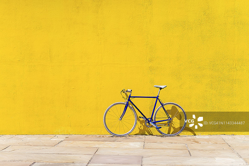 阳光明媚的日子里，自行车停在墙边的人行道上图片素材