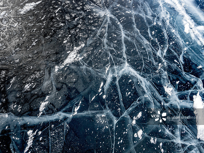 西伯利亚贝加尔湖上厚厚的固态冰层上的网状裂缝图片素材