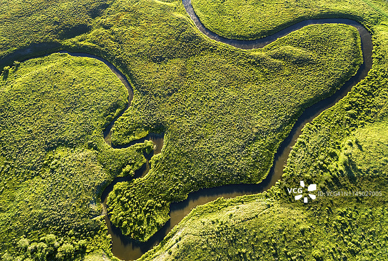 鸟瞰图在米勒维尔附近的绿色田野上俯瞰一条蜿蜒的小溪图片素材