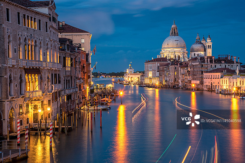 美丽的风景日落在著名的大运河上传统的贡多拉与历史上的圣玛丽亚德拉敬礼大教堂在背景在浪漫的金色夕阳在威尼斯，意大利图片素材