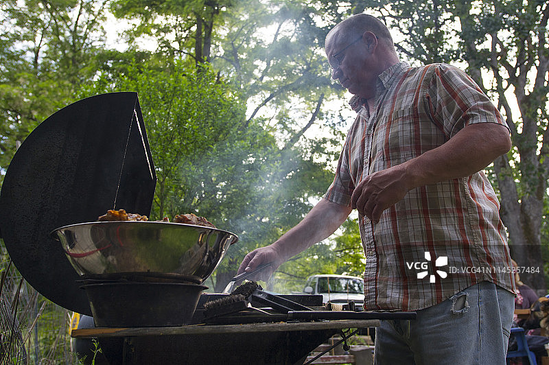 低角度的人烹饪烤鸡在森林烧烤图片素材