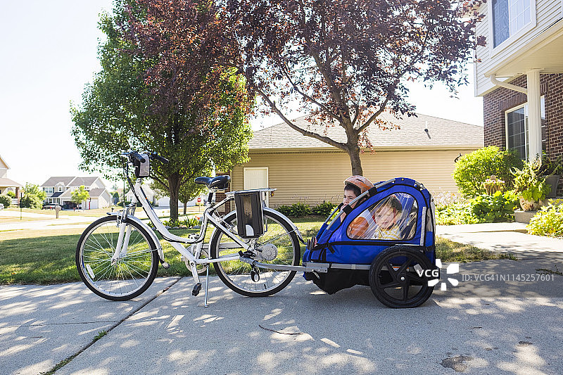兄弟俩坐在人行道上的自行车拖车里图片素材