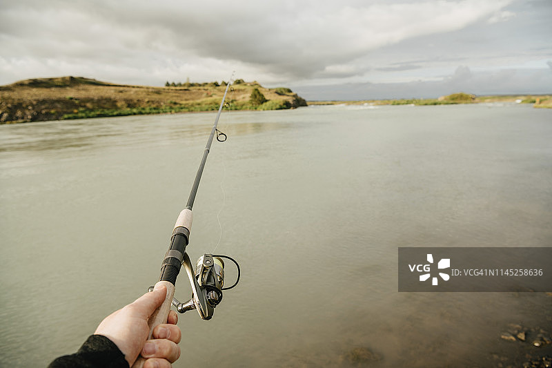 在冰岛阴天的湖面上捕鱼的人裁剪的手图片素材