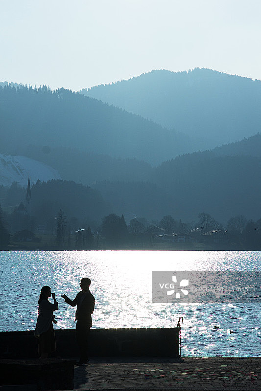 一对夫妇在德国巴伐利亚州泰根瑟湖畔欣赏日落图片素材