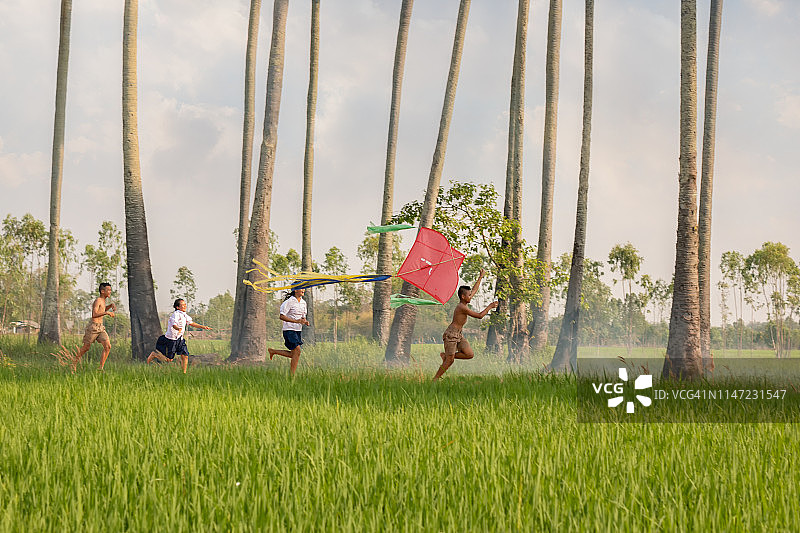 亚洲儿童农民在稻田里放风筝。图片素材