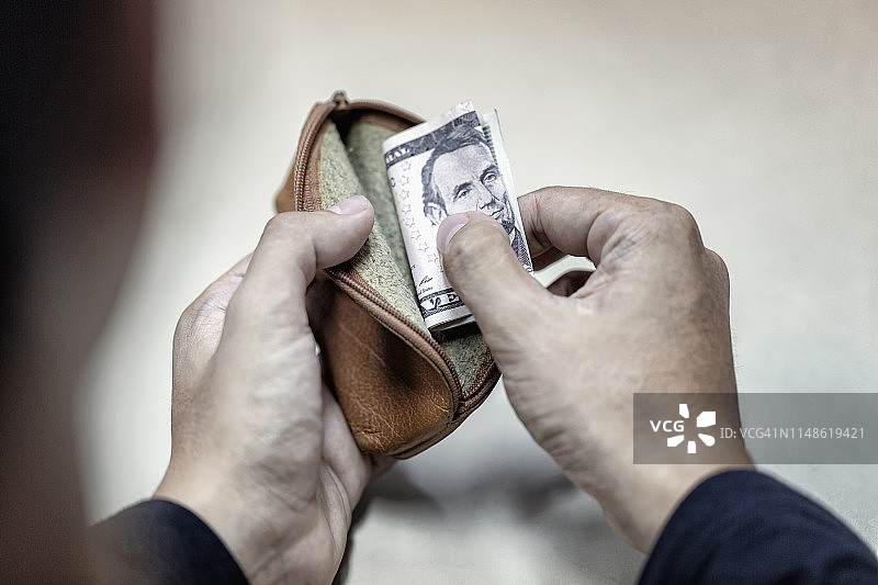 商人手里拿着钱包的人手里有一点钱。贫穷，贫穷，破产的概念。图片素材