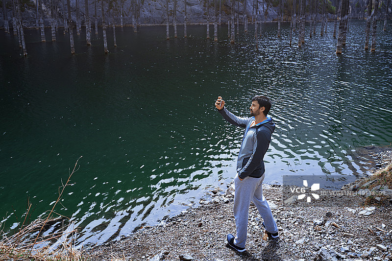 一名男子在山湖用智能手机拍照图片素材
